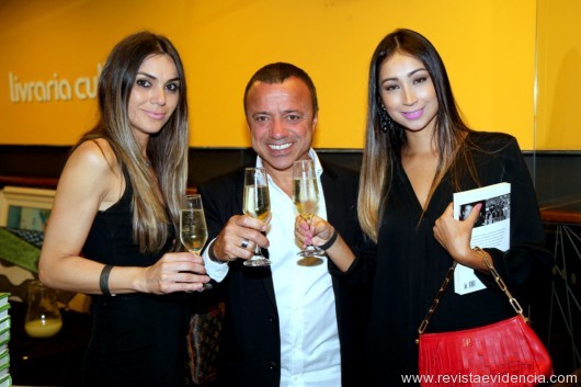 O empresário Araquém Pinto e emoldurado por Fabi Cor e a amiga Camila Sakon, brindando o sucesso do livro.