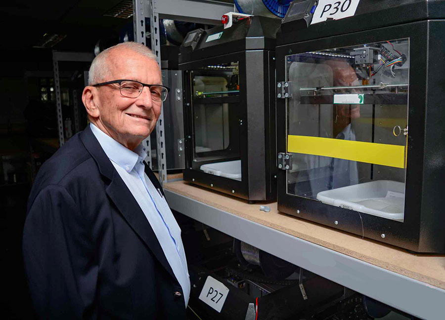 Sr. Thomas Case, fundador da Pés Sem Dor, entre as impressoras 3D de sua fábrica